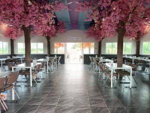 a dining room with tables and trees with pink flowers at เชียงรายฟิวชั่น in Ban Pa Faek