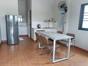 a kitchen with a table with chairs and a refrigerator at เชียงรายฟิวชั่น in Ban Pa Faek +6 photos