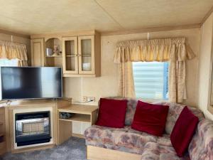 a living room with a couch and a flat screen tv at Helove Domki Karoliny in Hel