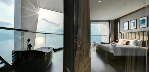 a bedroom with a tub and a bed and a window at Boton Blue Hotel & Spa in Nha Trang