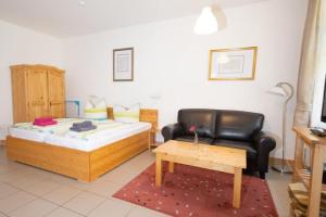 a living room with a bed and a leather chair at Ferienwohnung Forsthaus am Brocken, 35 qm, 1 Wohn-Schlafzimmer F1 in Ilsenburg