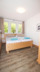 a bedroom with a wooden bed with two windows at Ferienwohnung Forsthaus am Brocken, 60 qm, 3 Schlafzimmer F5 in Ilsenburg