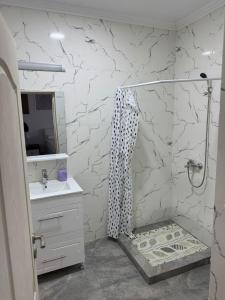 a white bathroom with a shower and a sink at AME Home in Ocna-Mureşului