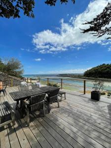 a wooden deck with a table and benches on the beach at La Maison Du Phare in Plérin