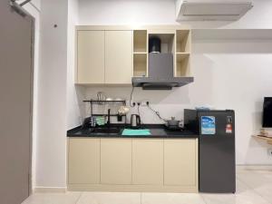 a kitchen with white cabinets and a black refrigerator at Bay Suite Likas by IGVC in Kota Kinabalu +8 photos