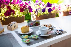 a table with cakes and a cup of coffee and flowers at House garden in Sperlonga