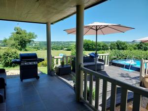 a deck with an umbrella and a grill and a pool at Cidre Bois in Saint-Sulpice-le-Dunois