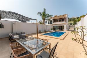 ベナルマデナにあるVB Camelia 4BR Villa by the beachのパティオ(テーブル、椅子付)、スイミングプールが備わります。