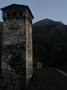 a tower on top of a building with a mountain at Bata GuesThouse in Adishi