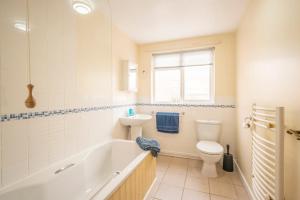 a bathroom with a tub and a toilet and a sink at Bovis Cottage, Southwold in Southwold +15 photos