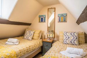a attic bedroom with two beds and a mirror at Bovis Cottage, Southwold in Southwold