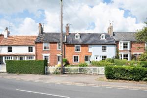 a row of brick houses with a white fence at Bovis Cottage, Southwold in Southwold