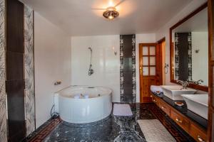 a bathroom with a large tub and two sinks at Silverstone Mansions Cottages in Manāli +42 photos