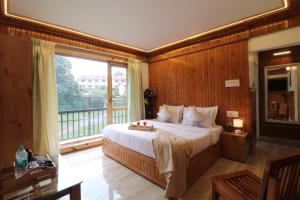 a bedroom with a large bed and a large window at Hotel Green Oak in Nainital