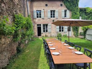 a long wooden table with chairs and an umbrella at Maison Coeurdacier 15 personnes 6 chambres in Monthureux-sur-Saône