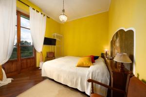 a yellow bedroom with a bed and a window at Casa nel Borgo Toscano- Casole d'Elsa in Casole dʼElsa