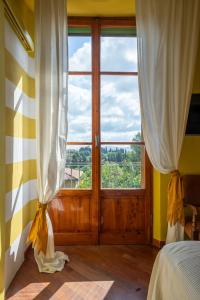 Un dormitorio con una gran ventana y una cama con cortinas. en Colorful Tuscan Retreat Steps from Casole City Center, en Casole dʼElsa