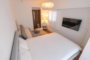 東京にあるSuke Home Oshiageの白いソファとテレビのあるリビングルーム