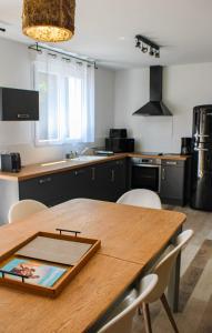 a kitchen with a wooden table and white chairs at Villa Thaïlande - Domaine Le Sherwood in Notre-Dame-de-Monts +3 photos