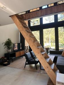 a wooden staircase in a living room with a large window at DomGalante - Nowoczesna stodoła na Pojezierzu Brodnickim in Grzywno