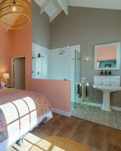 ein Schlafzimmer mit einem Bett und ein Badezimmer mit einem Waschbecken in der Unterkunft Crabapple Cottage, Cheverells Farm in Oudebrug