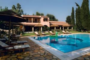 a pool with chairs and a house in the background at Corfu Club Apartments in Corfu