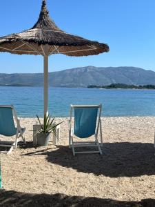 two chairs and an umbrella on a beach at ECO Aparthotel The Dreamers's Club in Lumbarda