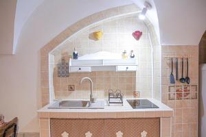Una cocina con fregadero y pared de azulejos. en Dimora Cenci - Almalusa Apulian Home by In Puglia service, en Martina Franca