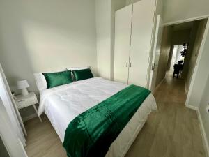 Un dormitorio con una cama grande con almohadas verdes. en Sunset on 13, en Bloubergstrand