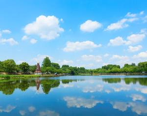 a lake with a windmill and clouds in the sky at 桜の宿 in Tokyo
