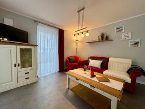 a living room with a red couch and a table at Aquamarin Ostseetraumsuite 01 in Neuhaus