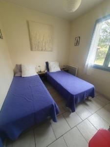 two beds in a room with purple sheets at maison residence les arros in Soulac-sur-Mer