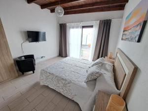 een slaapkamer met een bed, een tv en een raam bij Bella Blanca in Playa Blanca
