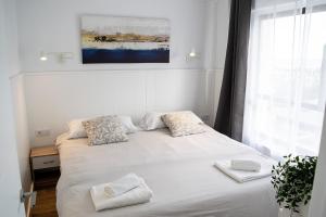 ein Schlafzimmer mit einem weißen Bett und zwei Kissen in der Unterkunft Ocean House Costa del Sol apartamentos varios by Costa del Sol Stay in Torremolinos + 23 Fotos
