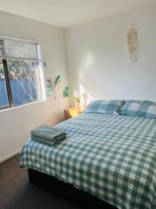 - une chambre avec un lit à damiers vert et blanc dans l'établissement Private room in sunny Bayfair, à Mount Maunganui