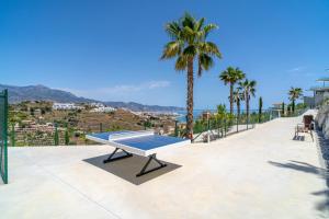 eine Tischtennisplatte auf einer Terrasse mit Palmen in der Unterkunft Vista Verde - Bayview Hills Luxury Resort with free padel & spa in Torrox