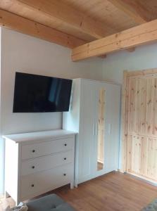 a room with a tv on a wall with a dresser at Dom nad Wodą in Krąg