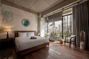 a bedroom with a bed and a large window at ANIMA Vietnamese Contemporary Art Boutique Hotel in Ho Chi Minh City