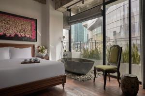 a bedroom with a tub and a bed and a chair at ANIMA Vietnamese Contemporary Art Boutique Hotel in Ho Chi Minh City