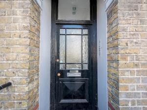 una puerta negra con una ventana en una pared de ladrillo en Pass the Keys Stylish Croydon apartment - Central London links, en Croydon