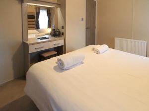 a bedroom with a white bed with towels on it at Glenridding Lodge in Windermere