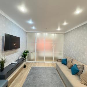 a living room with a couch and a flat screen tv at Great Cozy Apt in the heart of the city TU116 in Almaty