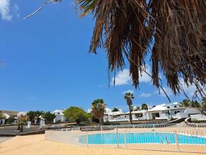 een zwembad voor een resort met palmbomen bij Bella Blanca in Playa Blanca