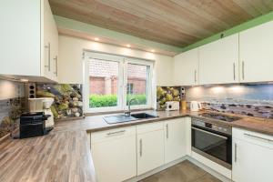 Avendorf auf FehmarnにあるHuus Strandgutの白いキャビネットと窓のあるキッチン