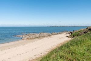 a sandy beach next to a large body of water at Villa du Mene - 60m plage & mer - Wifi in Mesquer
