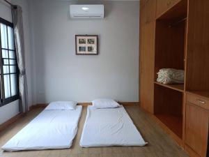 two beds are in a room with a shelf at เชียงรายฟิวชั่น in Ban Pa Faek