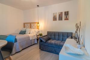 a bedroom with a bed and a blue couch at Estudio Nivalis El Rio in Monachil