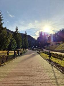 une route de briques dans un parc avec le soleil couchant dans l'établissement Family Residence Slănic-Moldova, à Slănic-Moldova