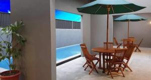a table and chairs with an umbrella and a pool at The Tanjung Bidadari Seminyak in Seminyak