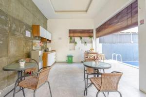 a kitchen and dining room with two tables and chairs at The Tanjung Bidadari Seminyak in Seminyak